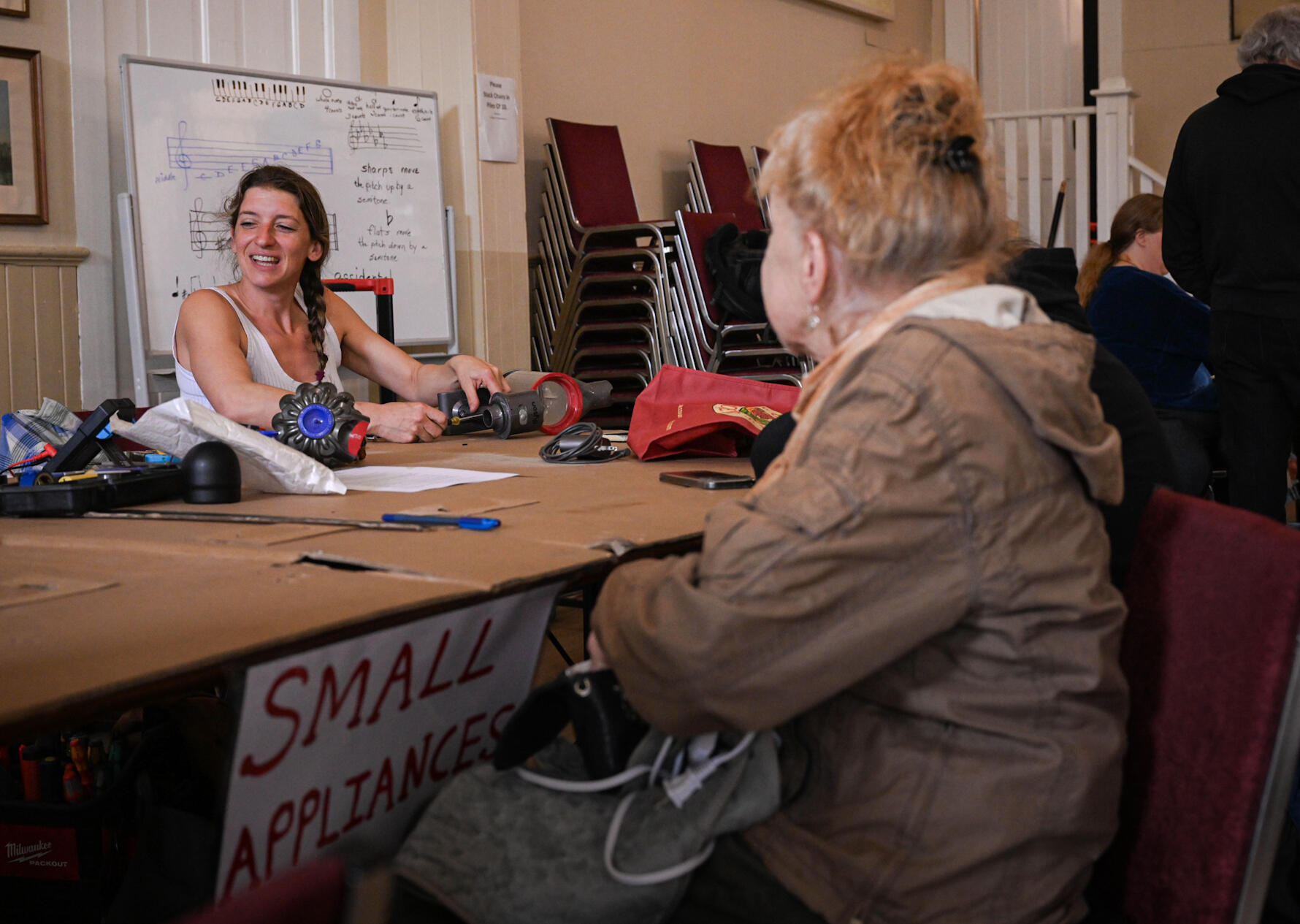 Volunteer interacting with attendee working on a vacuum cleaner